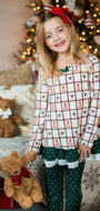 Young girl in festive pajamas holding teddy bears with Christmas decorations in the background